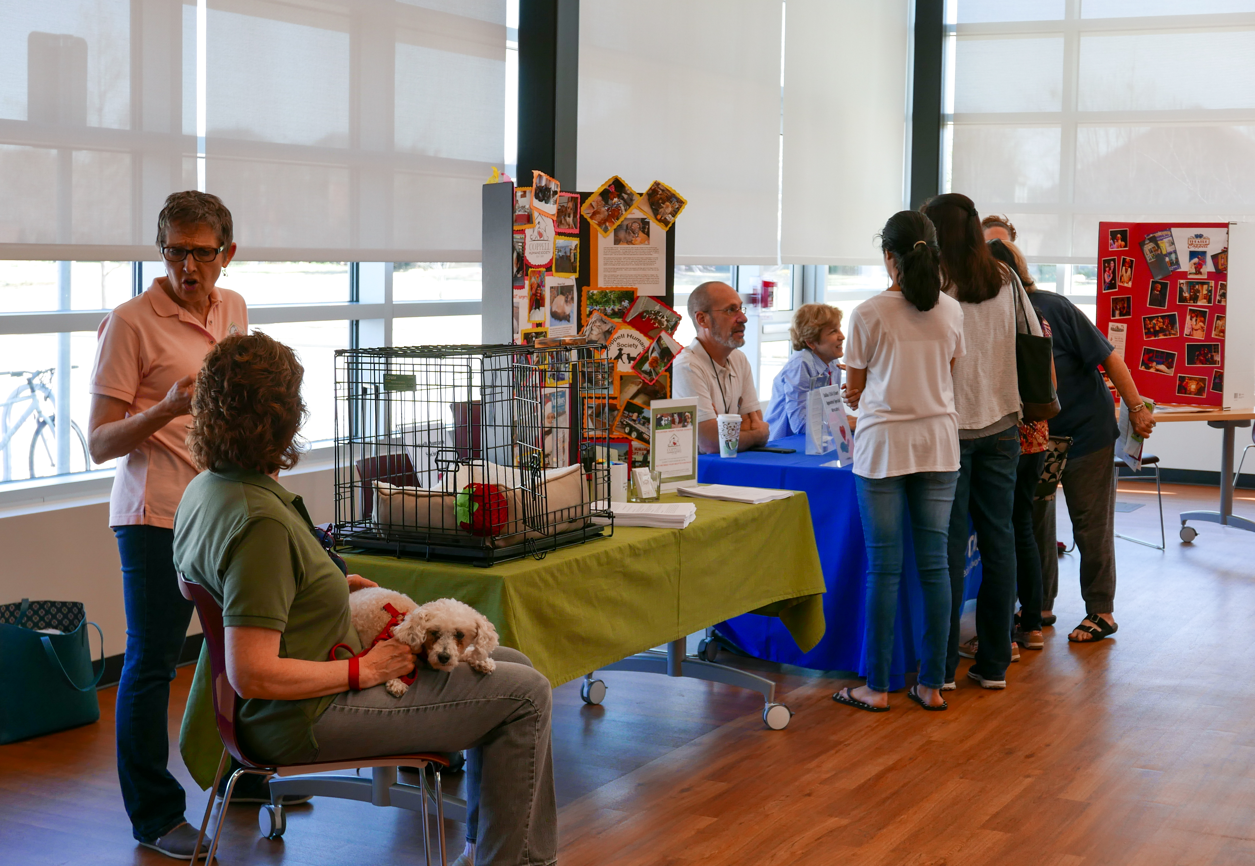 Photo from the 2017 Adult Volunteer Fair. Several people talking at a booth.