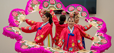 Asian women wearing traditional clothes dancing with feather fans.