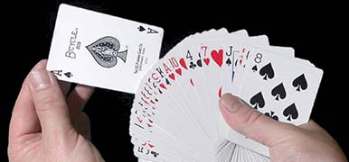Right hand holding several playing cards. The left hand is pulling out the Ace of spades.