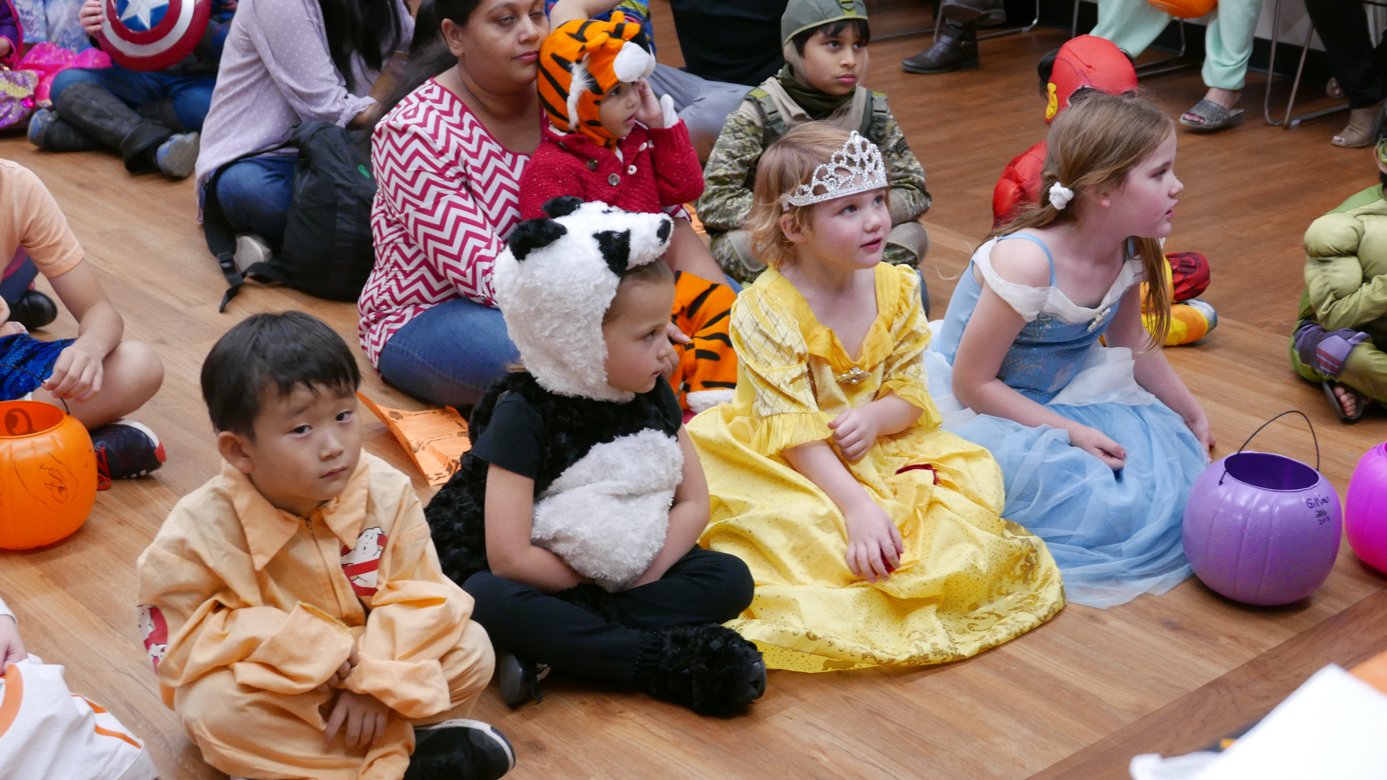 Kids in Halloween costumes sitting on the floor.