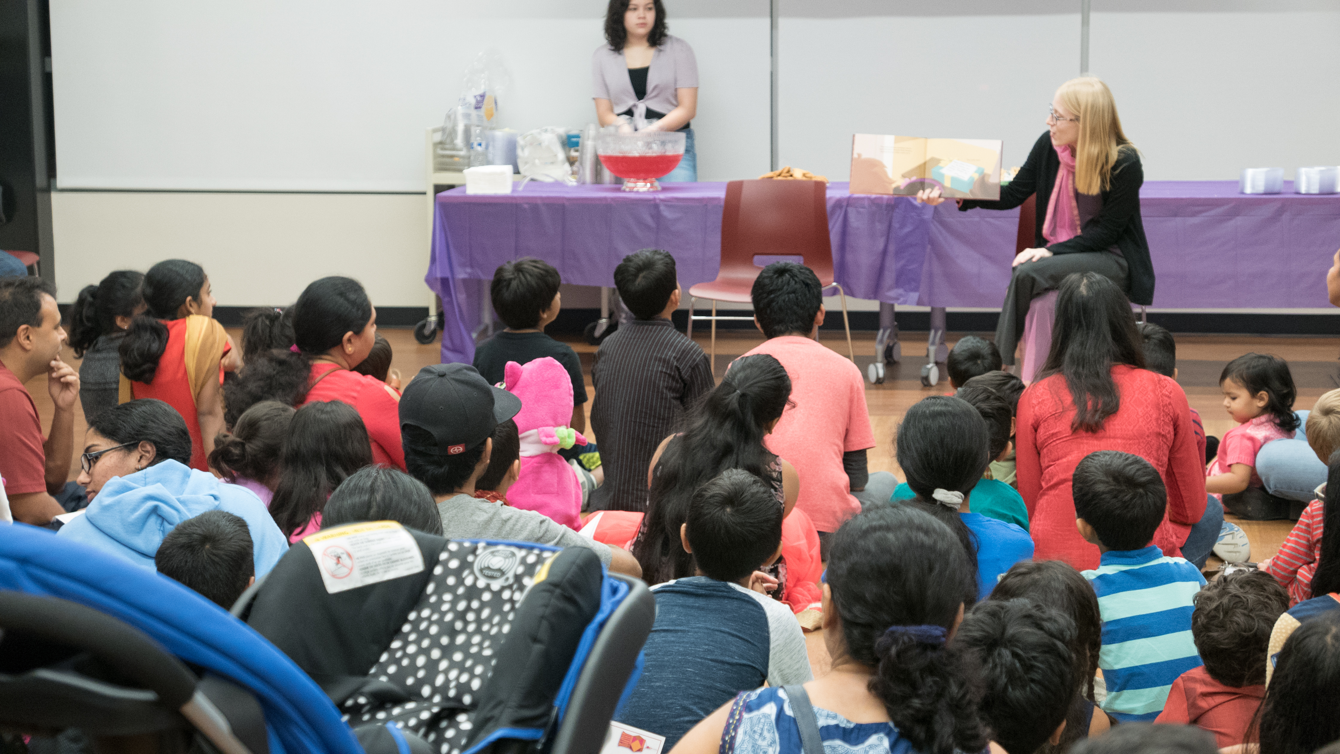 Photo from our 2018 Diwali Family Fun Night. A librarian is reading a story to the audience. 