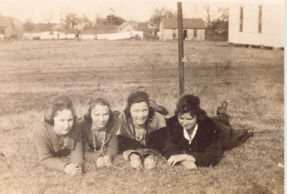 Old photo of a group of young women laying on the grass. 