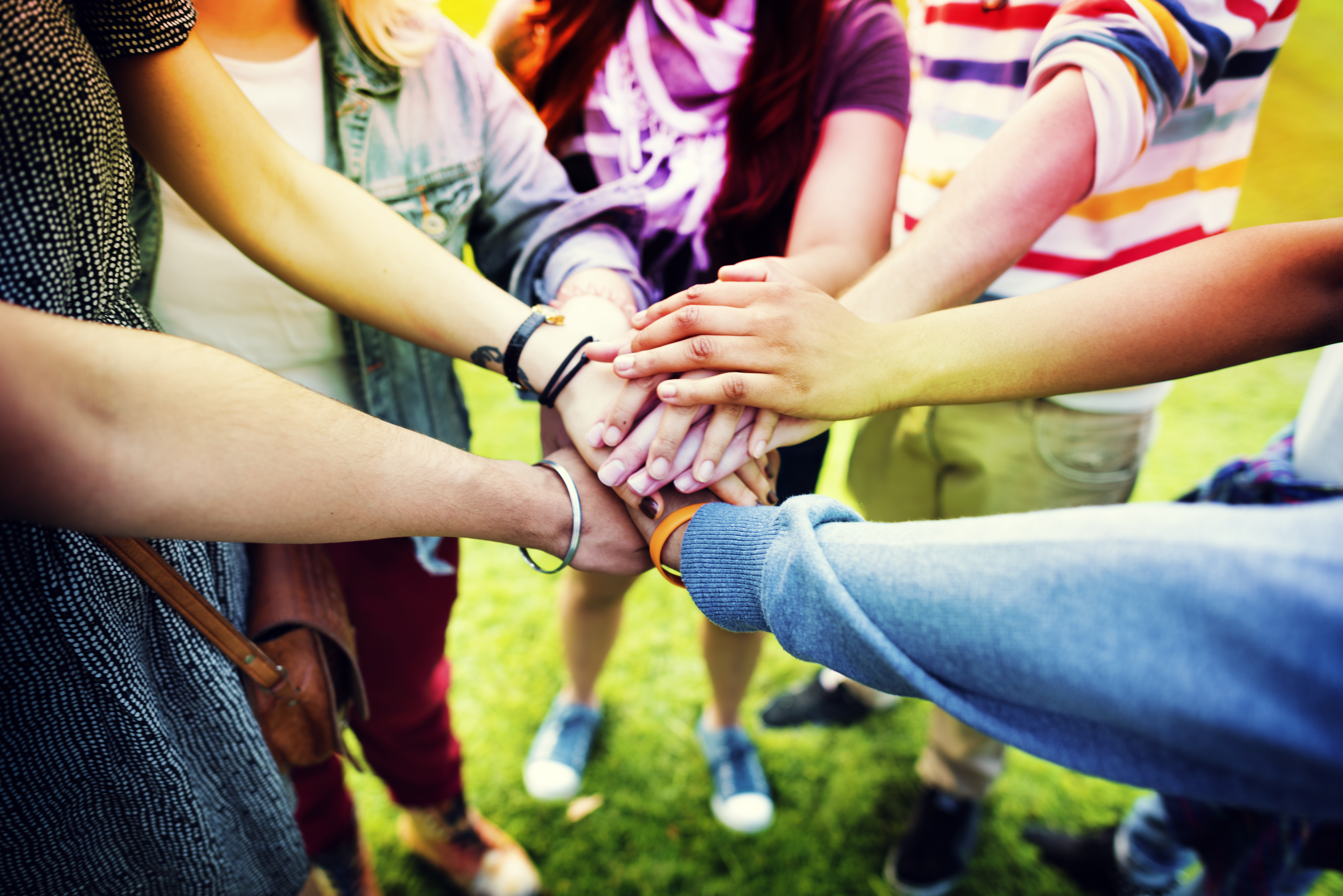 Group of people in a circle with hands gathered in the middle.