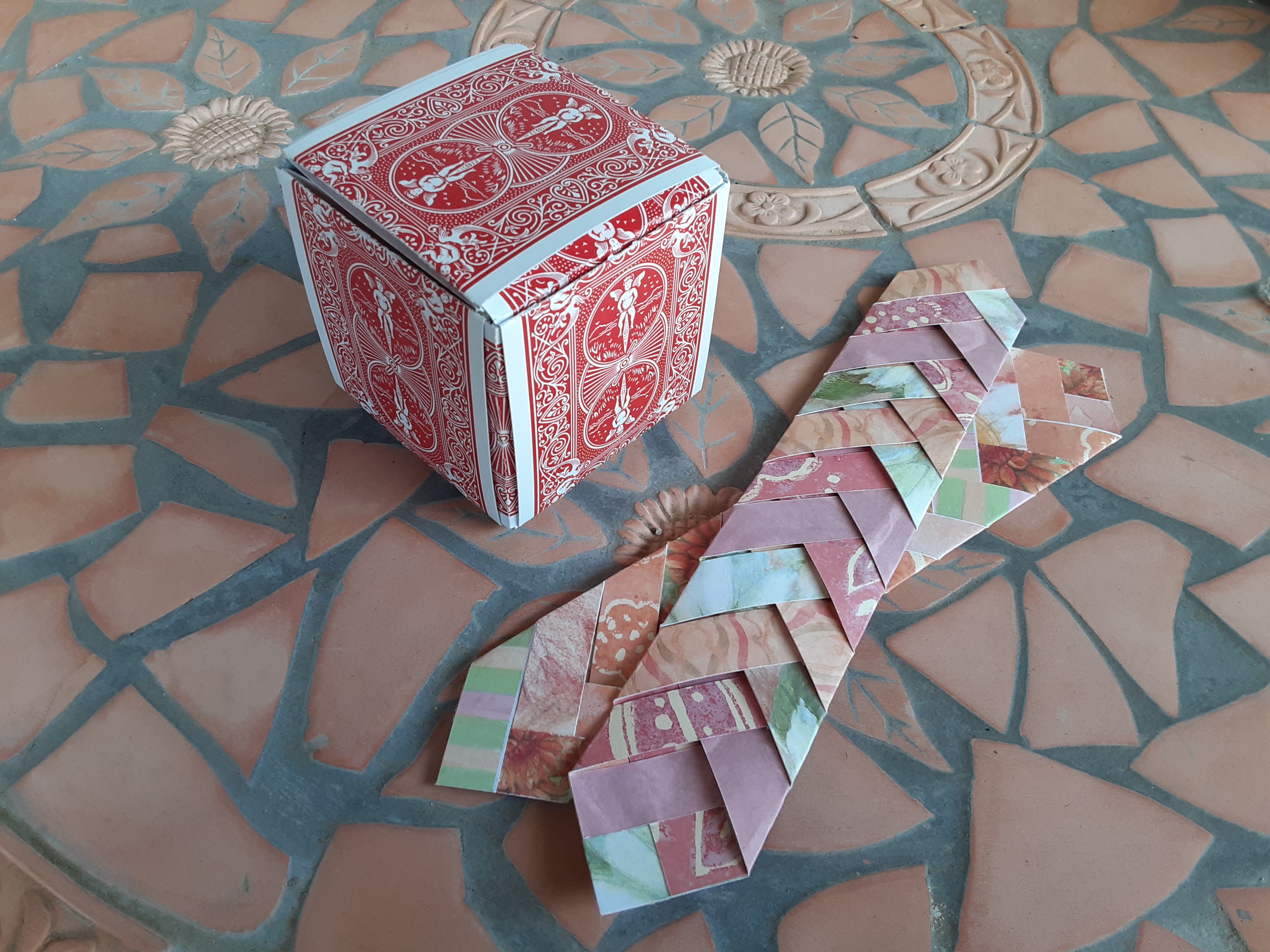 A box made of playing cards and two braided paper bookmarks.