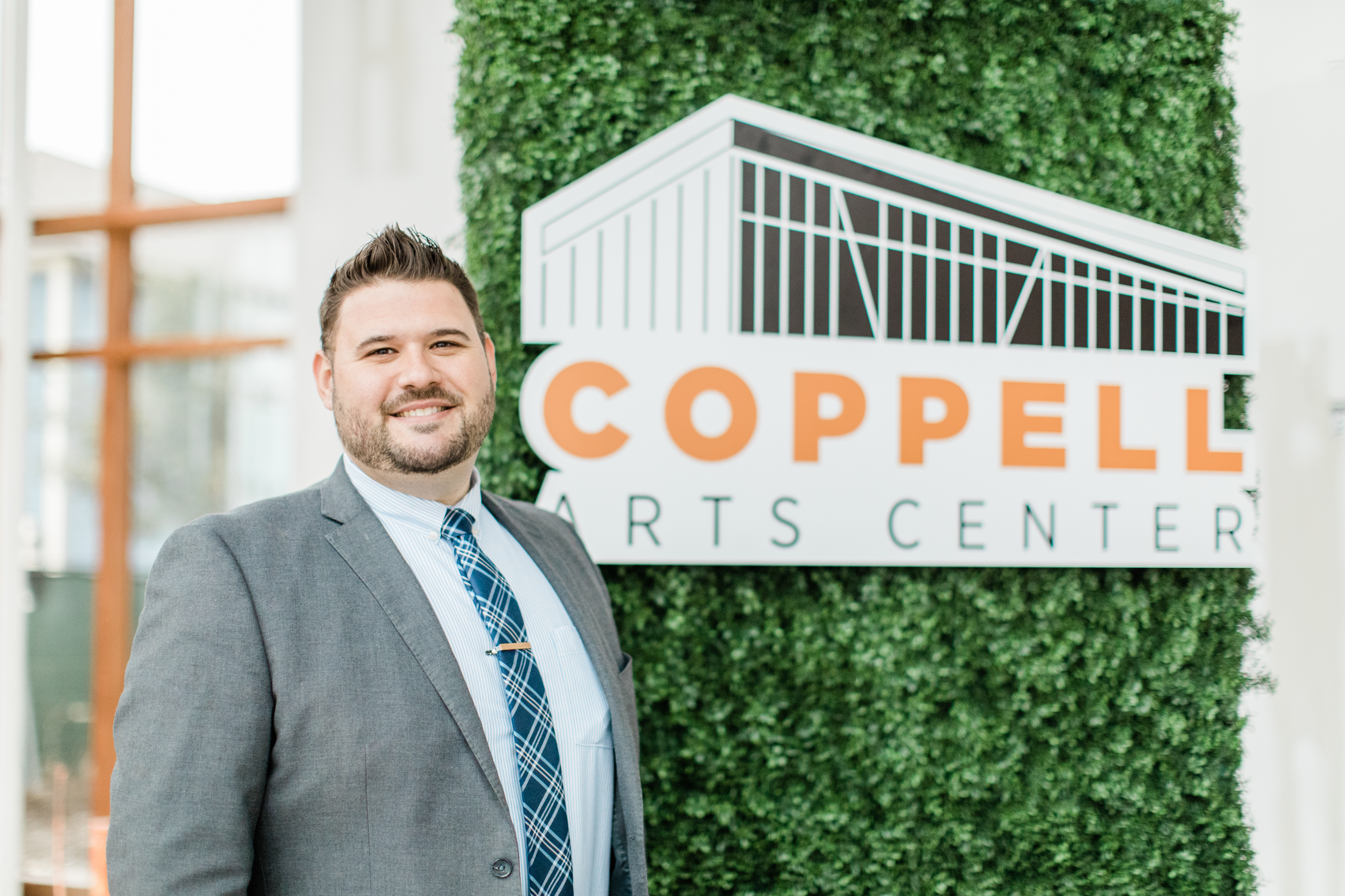 Alex Hargis standing in front of the Coppell Arts Center logo.