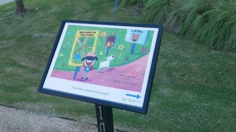 One book page displayed in a pedestal frame from the storybook walk located in a park.