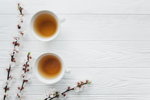 Two tea cups with flowers on a wooden background.