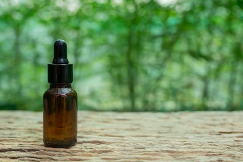 Eyedropper bottle in front of a green nature background.