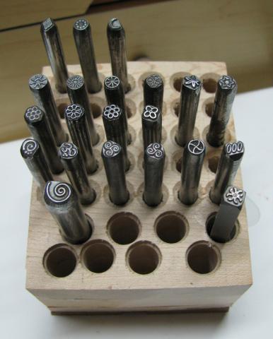 Metal stamping symbols in a wooden holder.