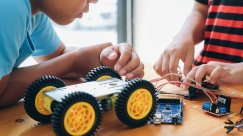 Two boys working on robotic cars.