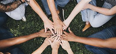 Image of multiple hands reaching into circle