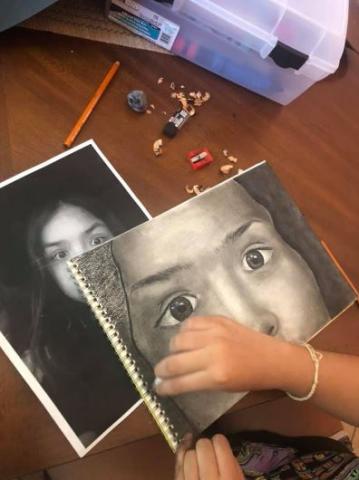 A student creating a charcoal portrait.