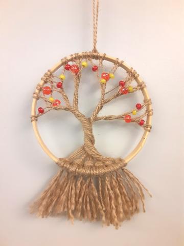 A tree made out of twisted twine inside a wooden hoop.  The tree is decorated with red, yellow, and orange beads.