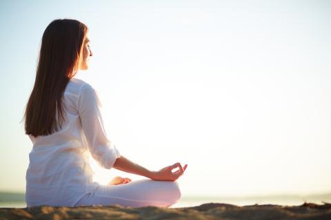 A woman sitting in a yoga pose on a beach