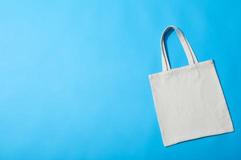 White cotton tote bag on a blue background.