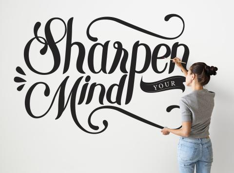 Female artist writing sharpen your mind on a white wall