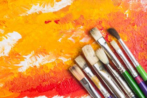 Paintbrushes on orange painted background.