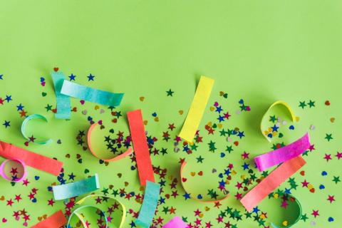 Colorful confetti and streamers on green background.