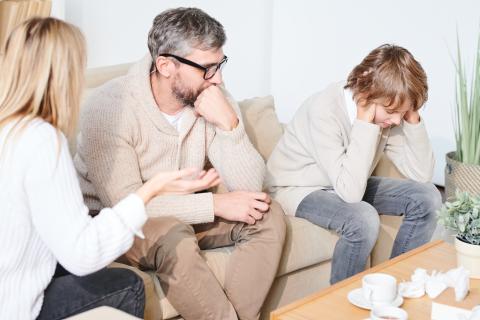 Unhappy teenager with parents on a couch