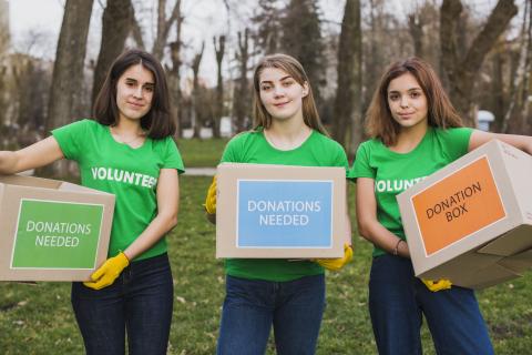 Three women volunteers holding donation boxes