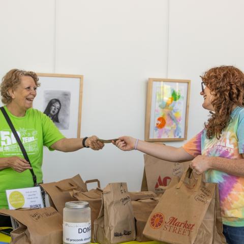 Woman handing money to another woman.