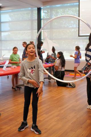 Kid flying paper dragon through a hula hoop.