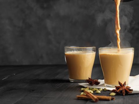 Two glass cups of hot chai with various spices featured.