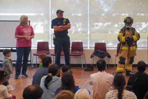 Firefighters and a librarian performing storytime.