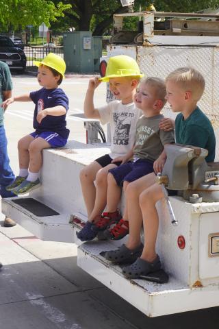 Four kids sitting on the back of a work truck.