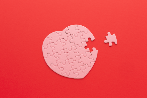 Pink puzzle in shape of a heart on a red background.