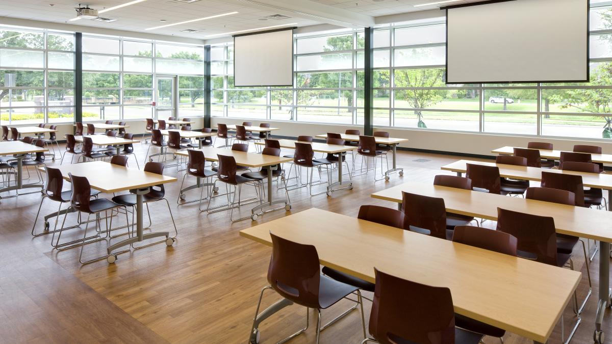 Meeting Room AB with various rectangular tables, multiple chairs, and two large screens