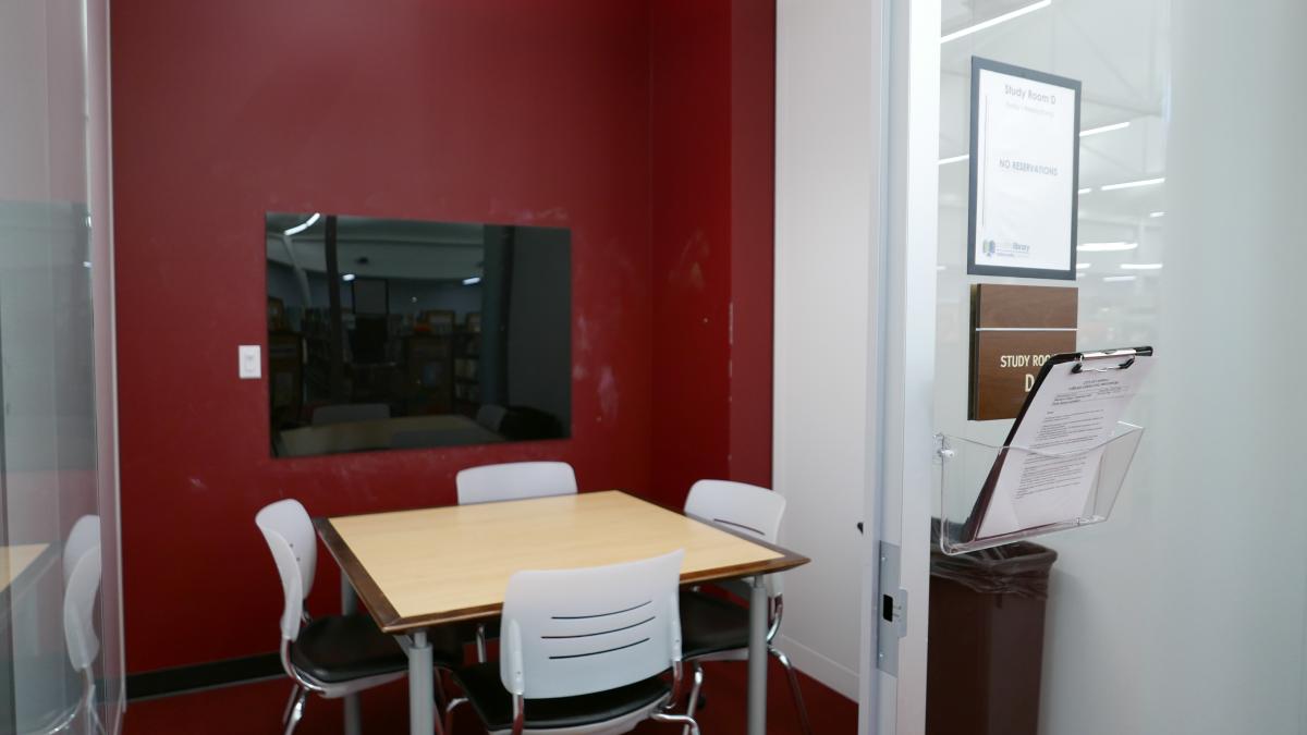 Study Room D with square table, four chairs, and large mounted glass board