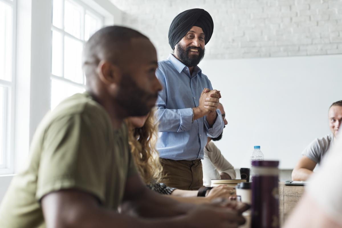 Indian man standing and talking in a group. 