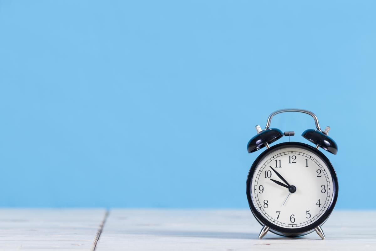 An alarm clock on a table with a blue background.