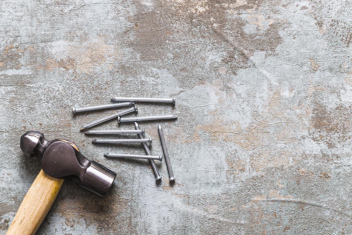 Hammer and nails in the bottom left corner on a weathered grey background.