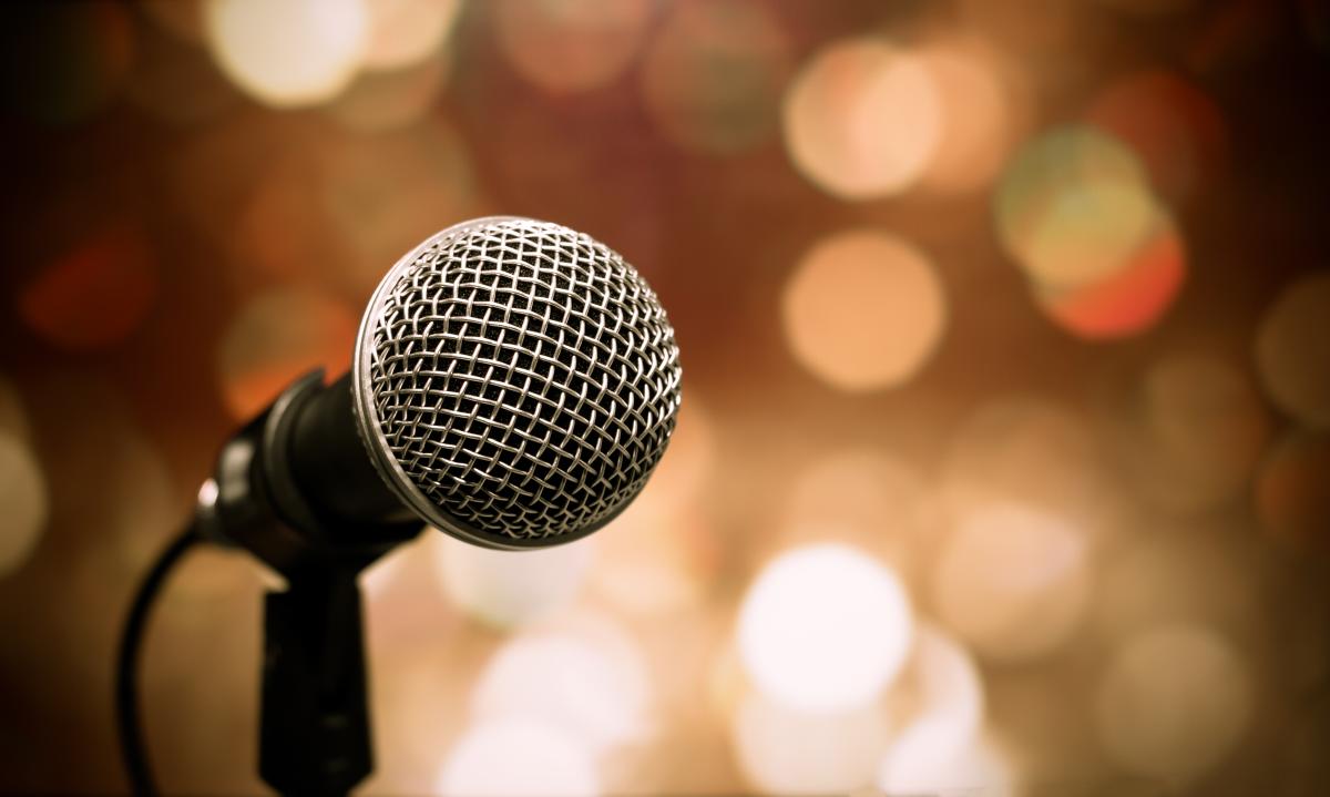 Close up of a microphone in front of stage lights.