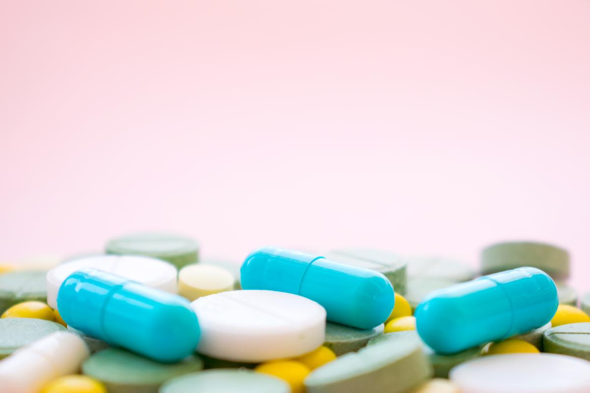 Various pills on a pink background.