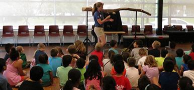 Group of kids sitting on the floor watching an animal show with live animals.