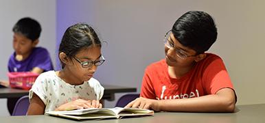 Girl reading to a teenage boy.