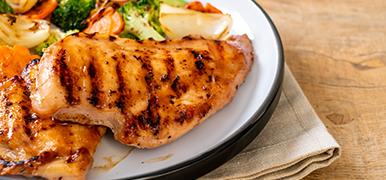 Grilled chicken and vegetables on a white dinner plate.