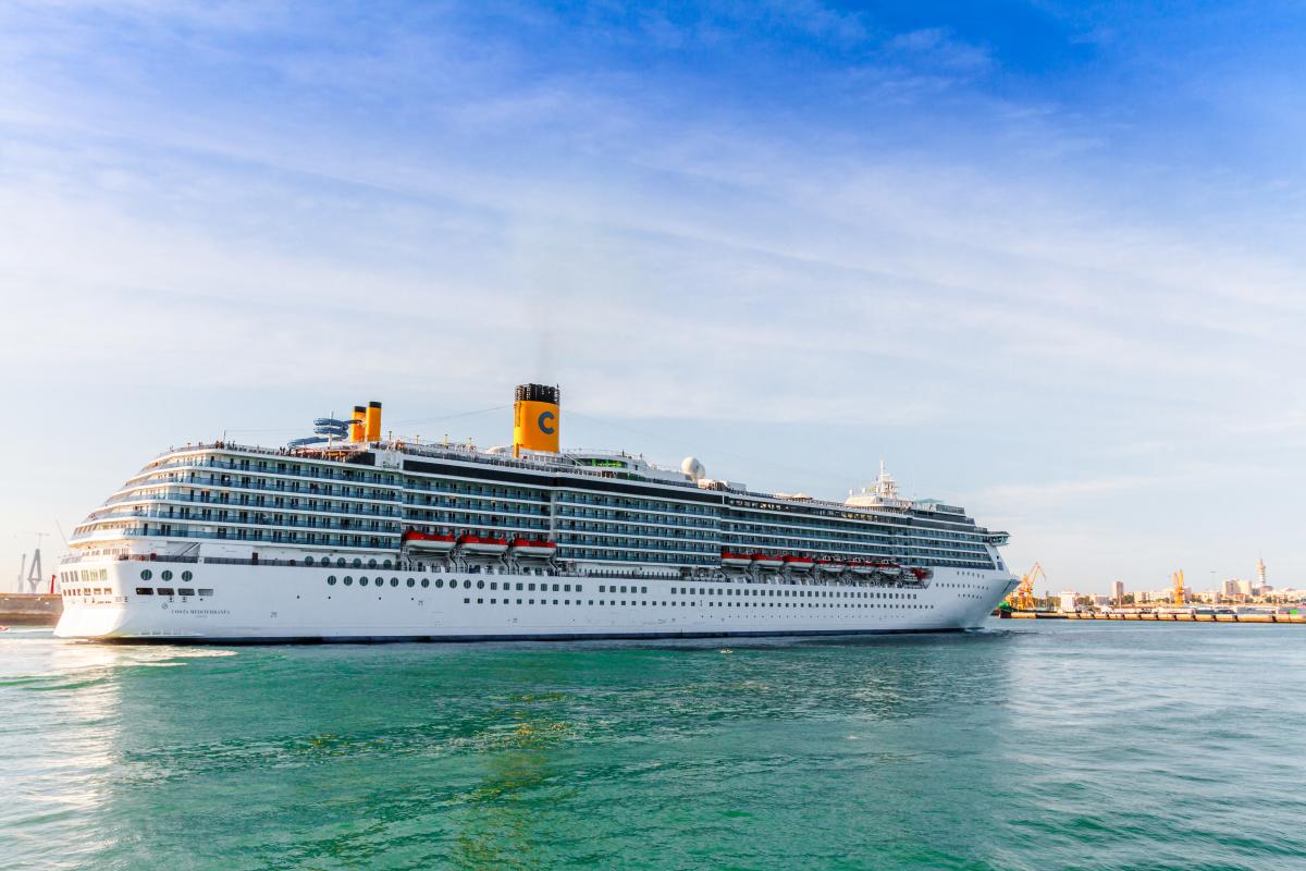 Cruise ship on the open water with a blue sky.