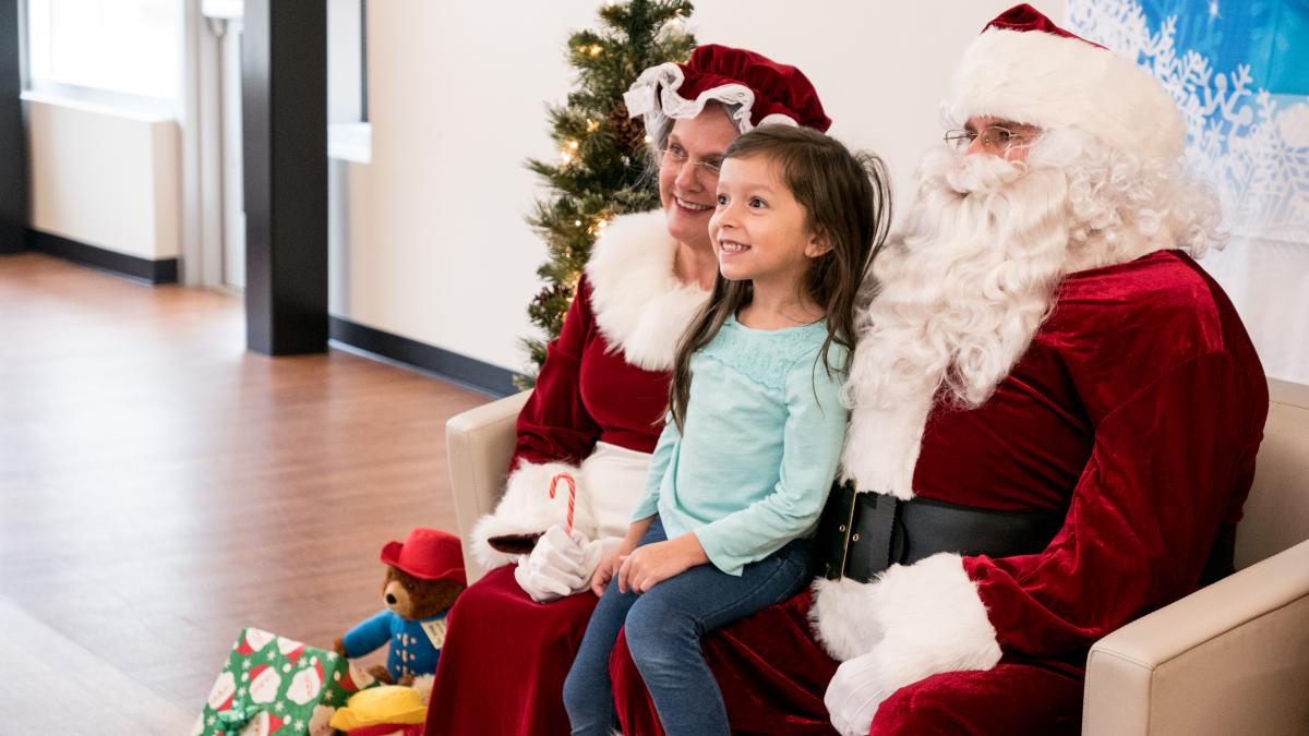 Santa and Mrs. Claus with a girl on their lap.