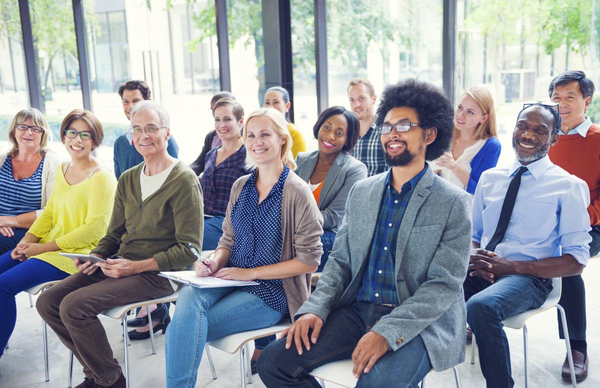 Group of diverse people sitting and listening to someone.