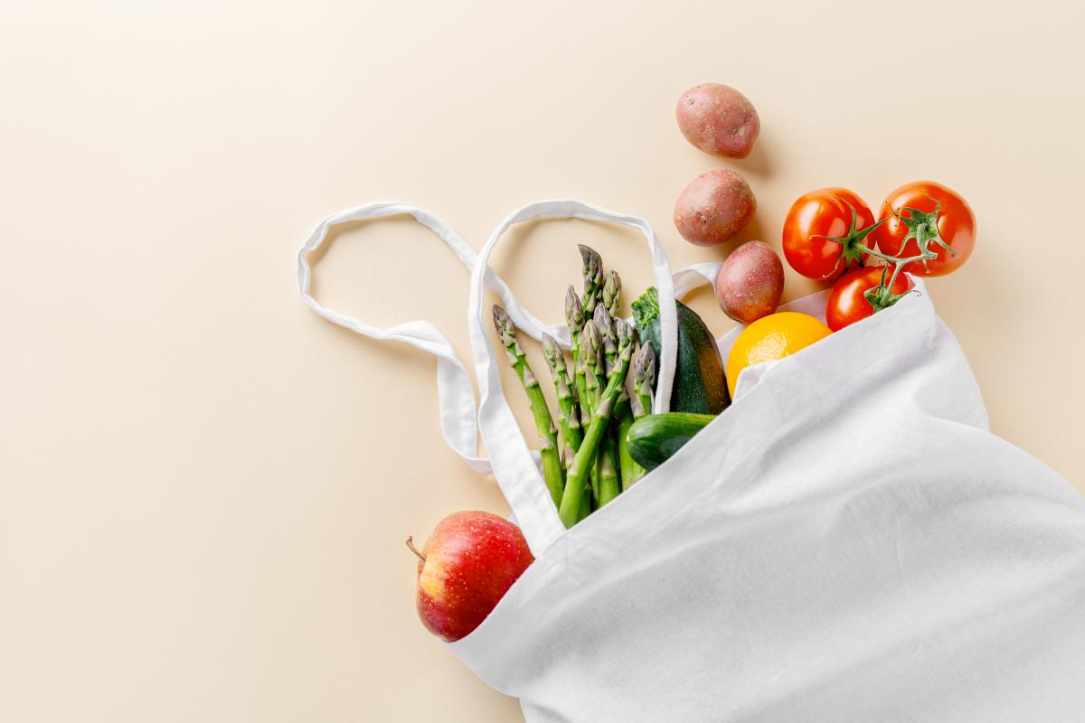 Various vegetables in a white cloth bag.