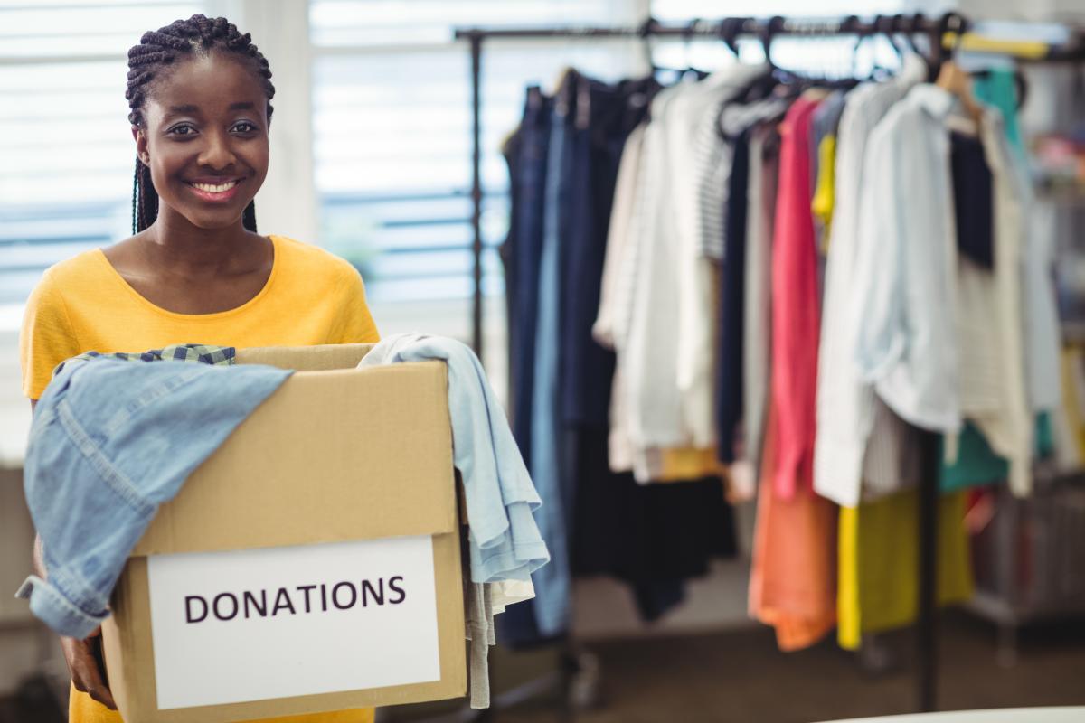 Woman smiling holding a box with clothes.