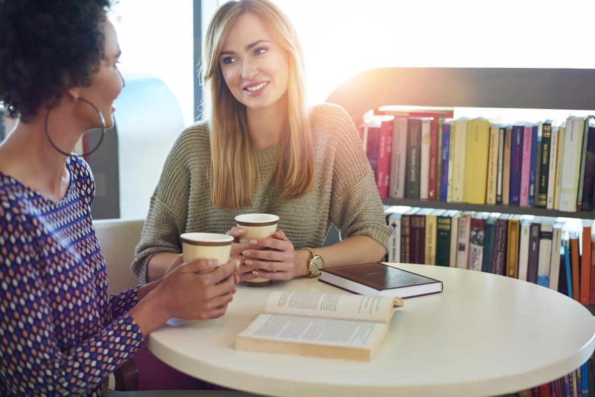 Two women at a table holding coffee cups