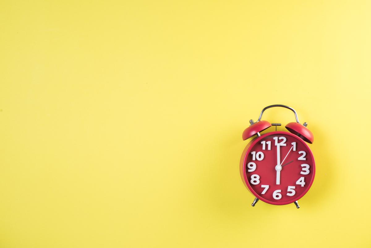 Red alarm clock on a yellow background.