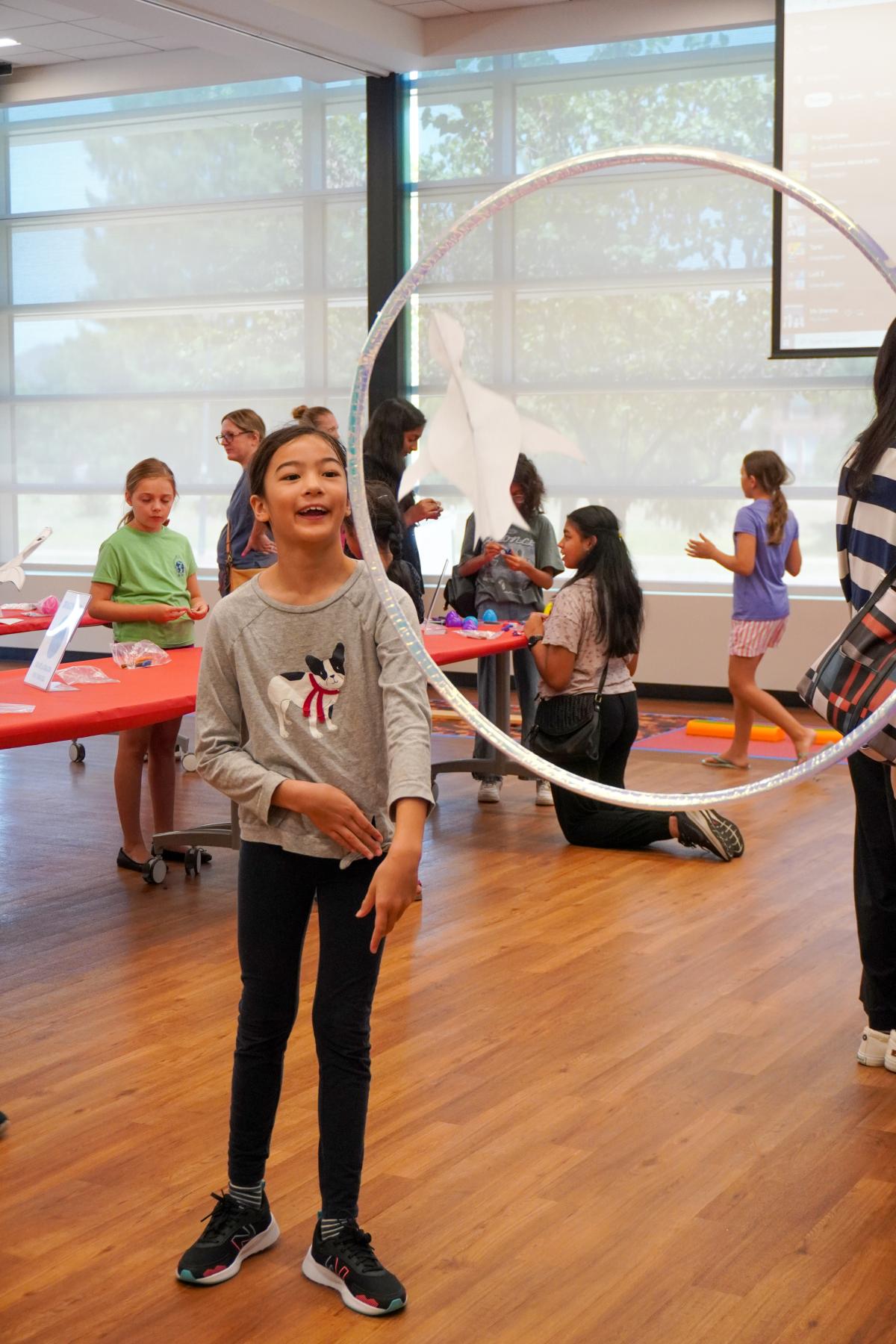 Kid flying paper dragon through a hula hoop.