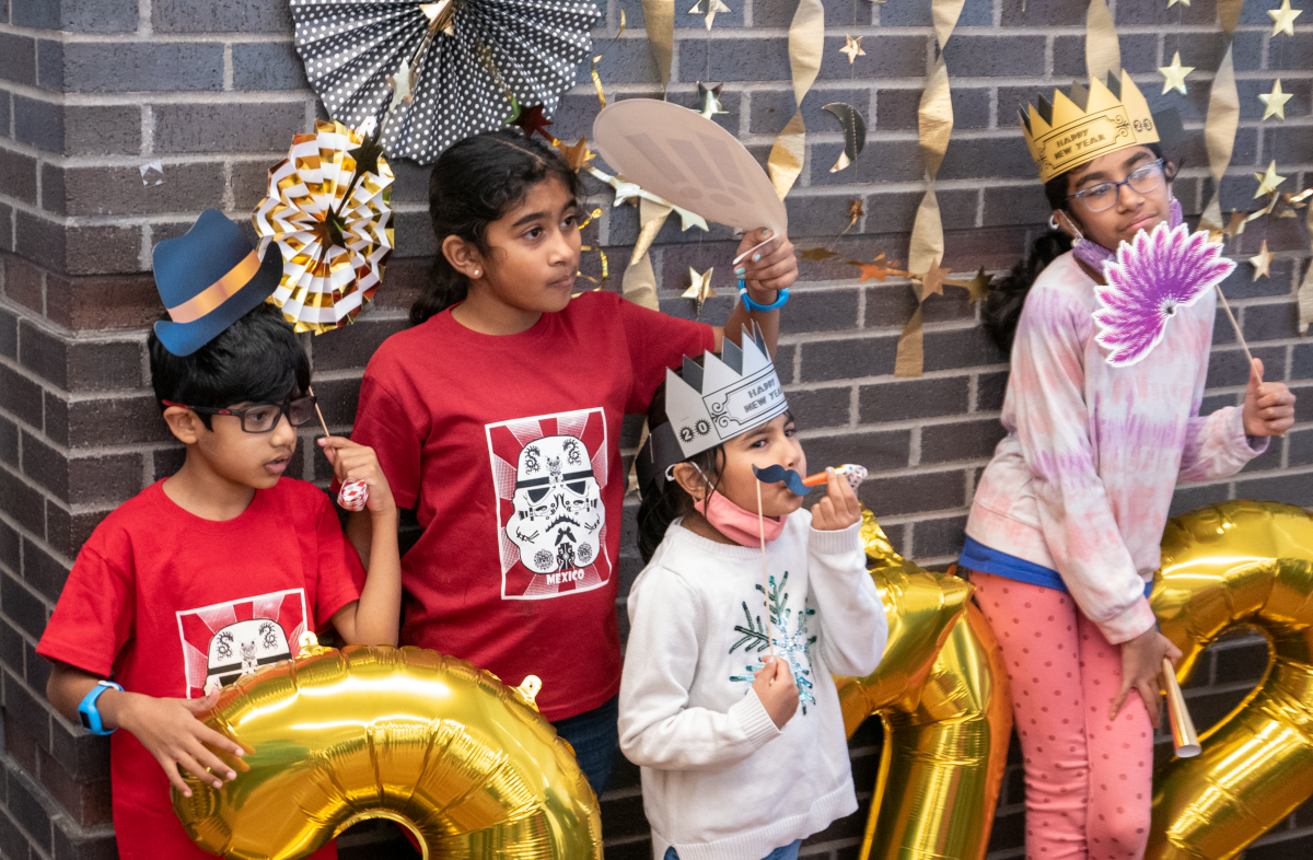 Children with New Year's Eve props posing in front of a brick wall.