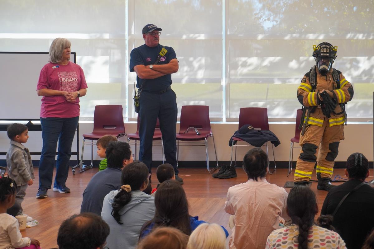 Firefighters and a librarian performing storytime.